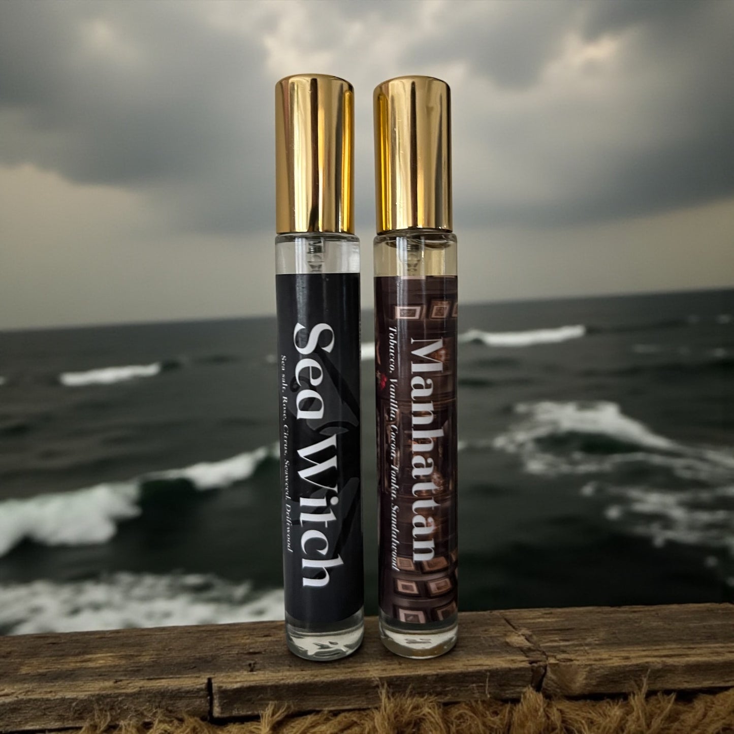 Two perfume bottles labeled 'Sea Witch' and 'Manhattan' on a wooden surface with an ocean background.