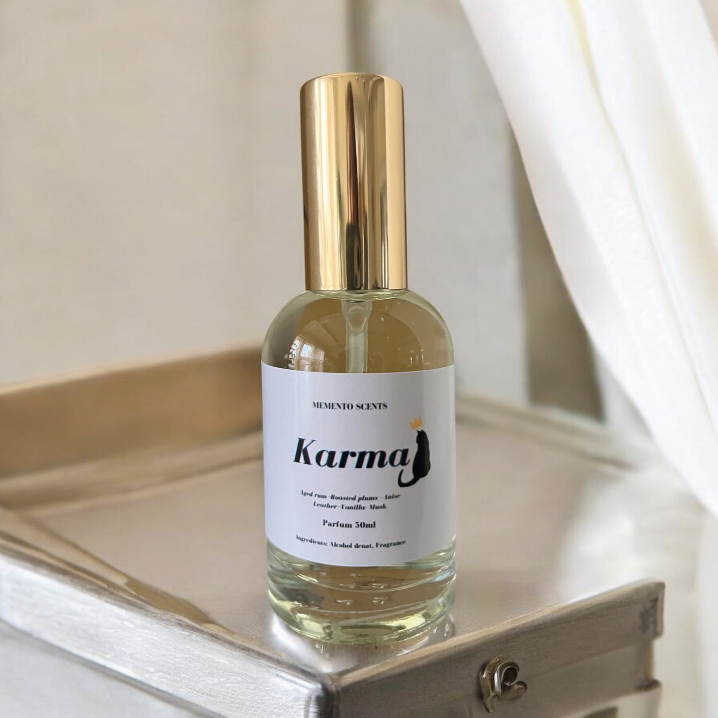 Karma perfume bottle, surrounded by elements of sun-soaked leather, roasted plums, and sweet musk, with notes of aged rum, vanilla, amber, and patchouli.