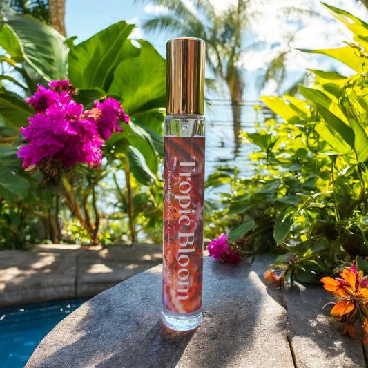 A bottle of Tropic Bloom perfume surrounded by lush tropical flowers with notes of peaches , passionflower, jasmine and coconut