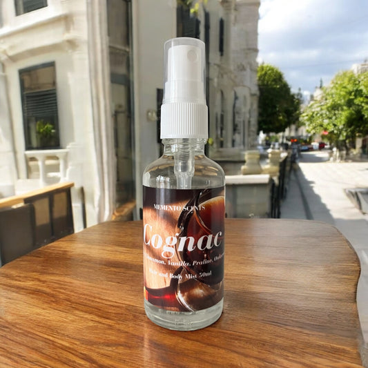 A bottle Of Cognac hair and body mist on a wood table with notes of cognac, praline, vanilla and cinnamon