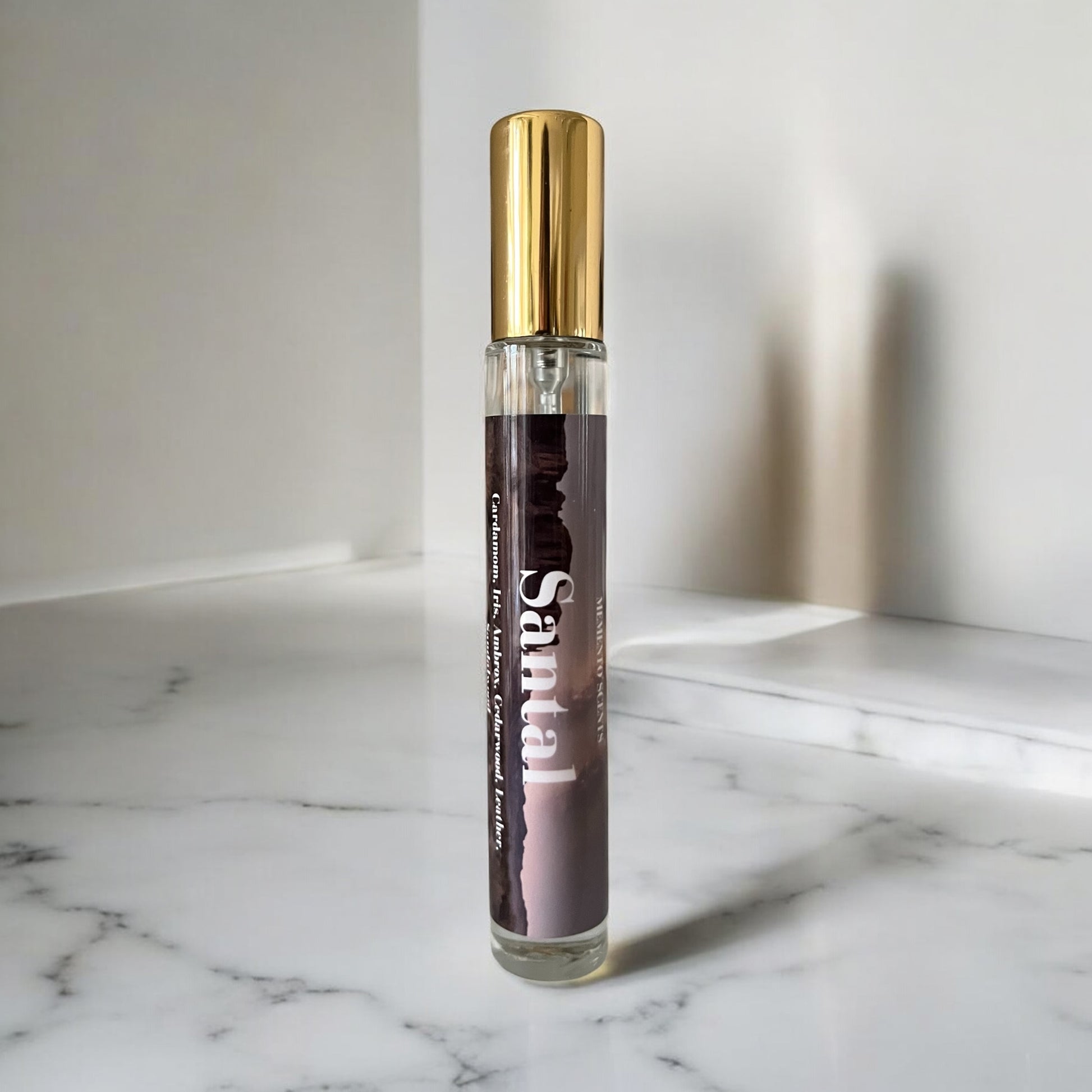 Santal perfume bottle with gold cap and dark label on a marble surface