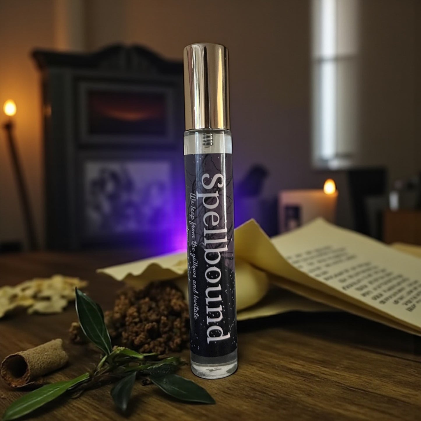 bottle of perfume labeled 'Spellbound' on a wooden surface with herbs and candles in the background