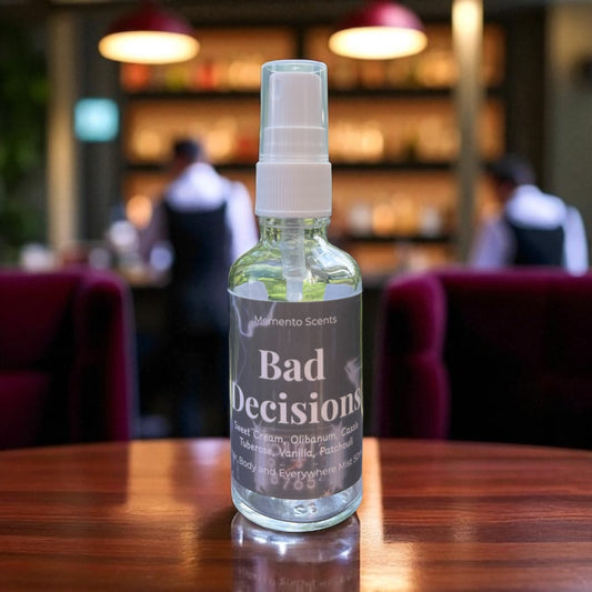 Bottle of 'Bad Decisions' scented spray on a table with a blurred cafe background