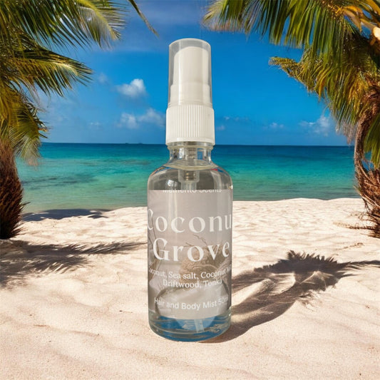 A glass spray bottle of Hair and body mist on a beach with the ocean in the background named Coconut Grove