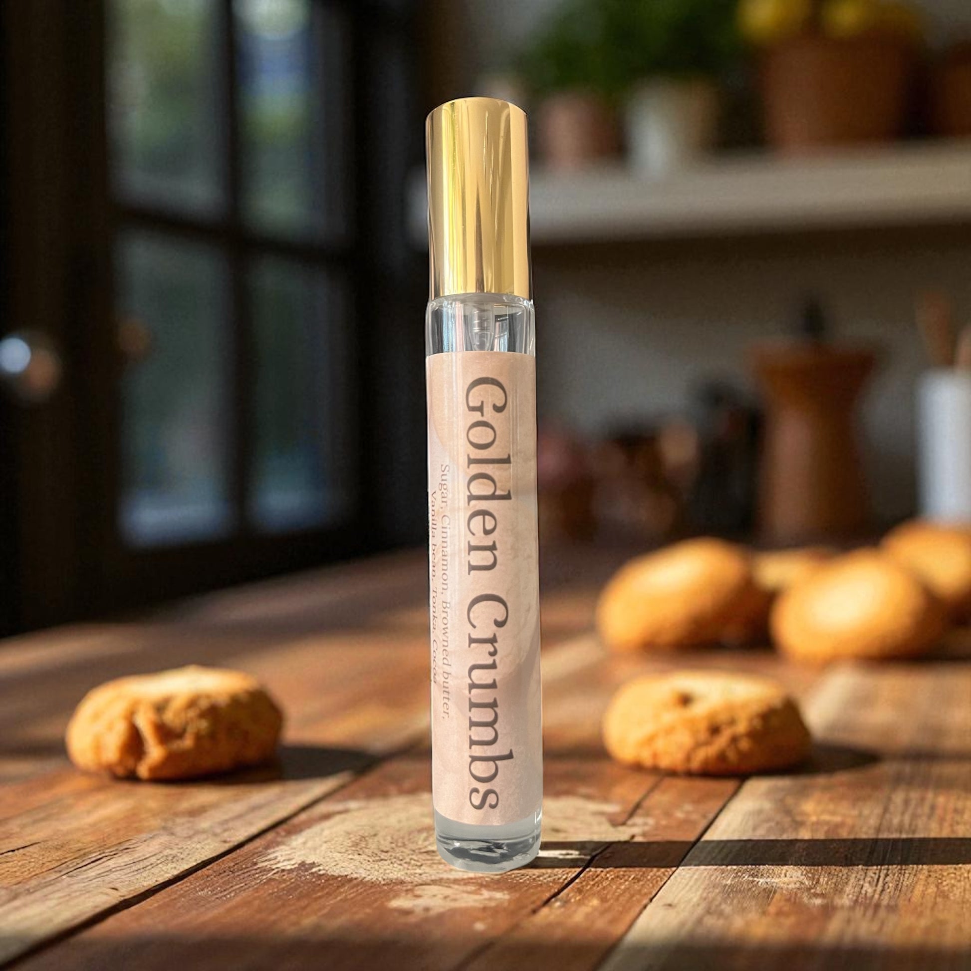 Perfume bottle labeled 'Golden Crumbs' on a wooden surface with cookies in the background
