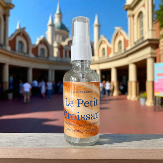 Bottle of 'Le Petit Croissant' Hair and body mist on a ledge with a blurred France pavilion in Epcot