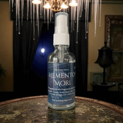 Memento Mori hair and body mist spray bottle on a wooden surface with a blurred background