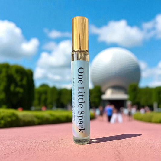Perfume bottle labeled 'One Little Spark' with the scenic background of Epcot