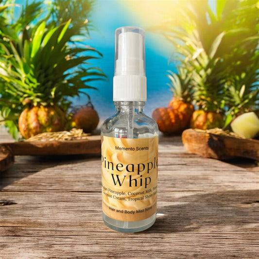 A glass spray bottle of Hair and Body Mist on a wooden table surround be pineapples  named Pineapple Whip