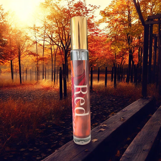 Red perfume bottle on a wooden platform with autumn trees in the background