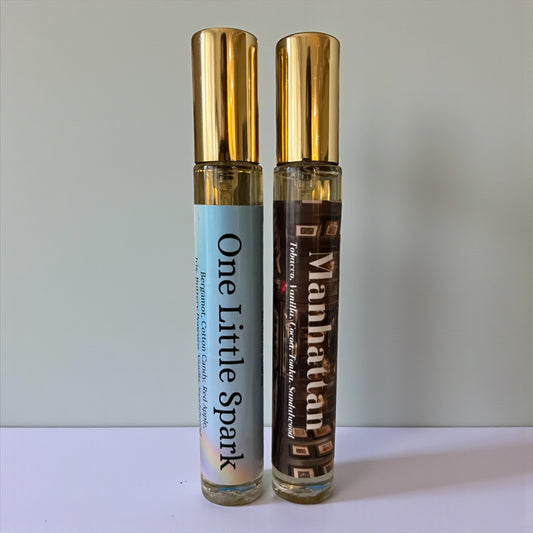 Two small bottles labeled 'One Little Spark' and 'Manhattan' on a light gray background.