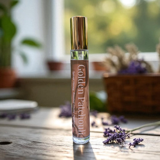 Perfume bottle of 'Golden Patchouli' essential oil on a wooden surface with lavender flowers.